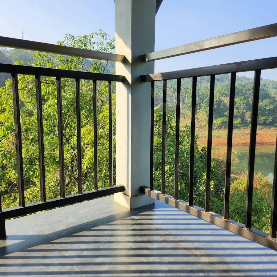 Black metal railing around a balcony looking out over trees